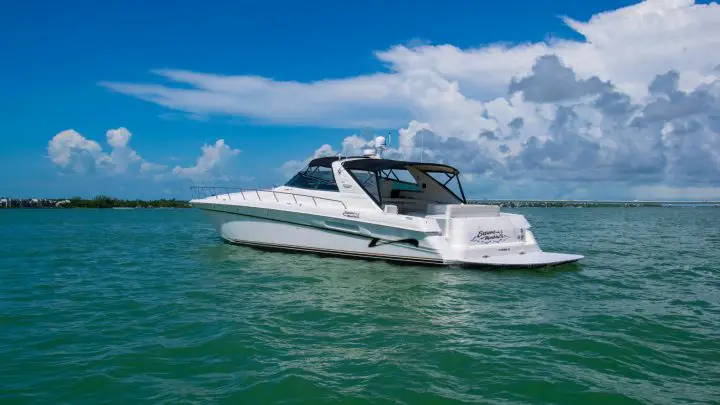 white and blue boat on sea under blue sky and white clouds during daytime